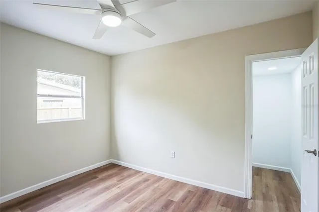 an empty room with a window and a fan