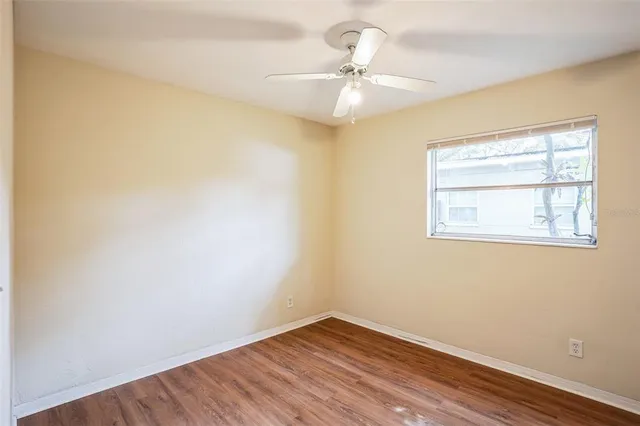 an empty room with a window and wooden floor