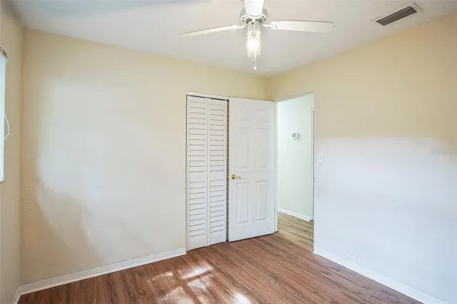 an empty room with wooden floor and ceiling fan