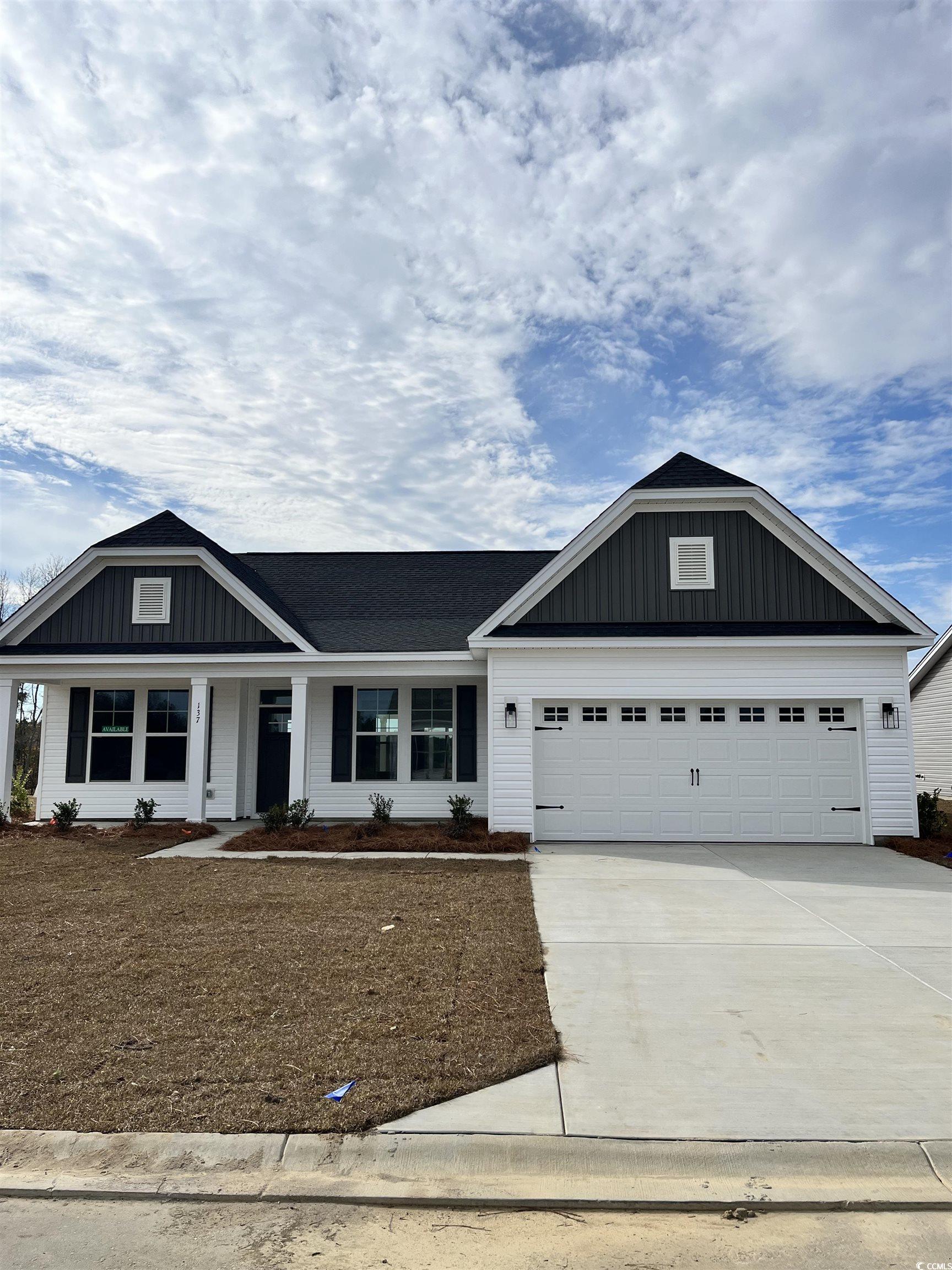 View of front of property with a porch, driveway, a garage, and board and batten siding