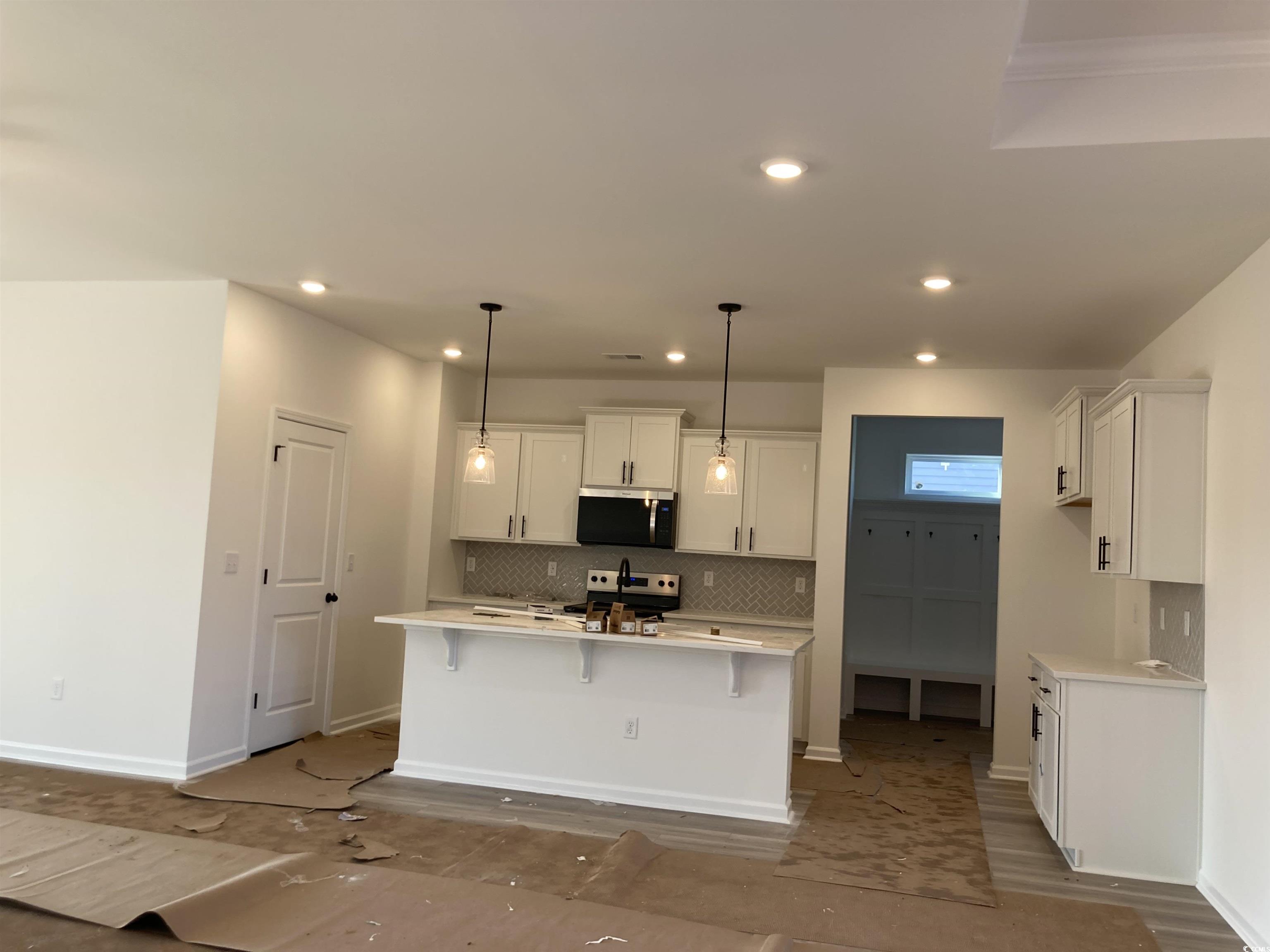 137 River Birch Drive Loris, SC 29569 - Photo 2 of 17 Kitchen with hanging light fixtures, a kitchen island with sink, a breakfast bar, decorative backsplash, and white cabinets