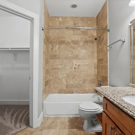 a bathroom with a granite countertop bathtub sink vanity mirror and toilet