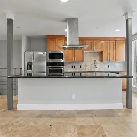 a kitchen with stainless steel appliances granite countertop a refrigerator a stove and a sink with wooden floor