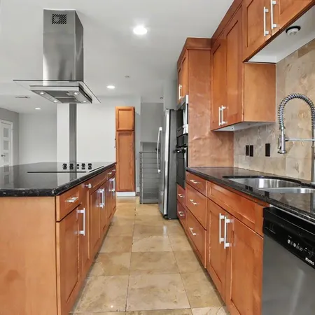 a large kitchen with stainless steel appliances a sink and a refrigerator