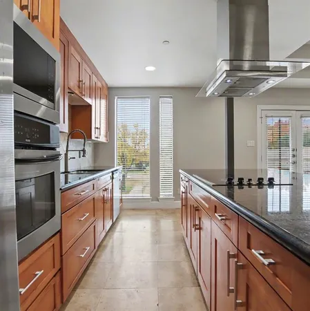 a large kitchen with stainless steel appliances a large counter top a stove and a sink