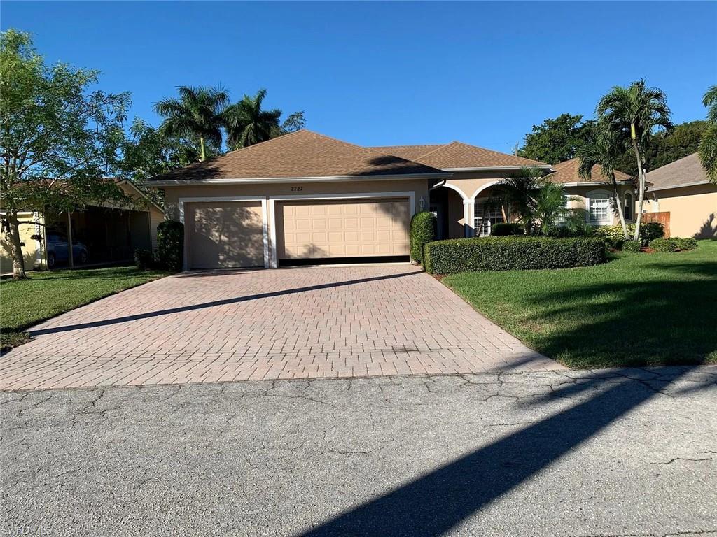 View of front facade with a front lawn, decorative driveway, a garage, and stucco siding