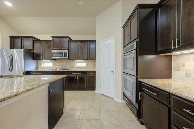 a kitchen with stainless steel appliances granite countertop a sink stove and refrigerator