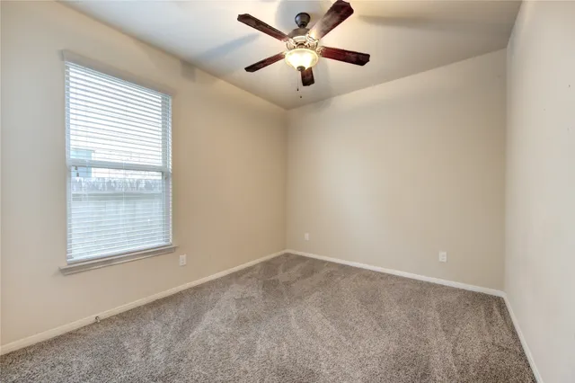 an empty room with a window and a fan