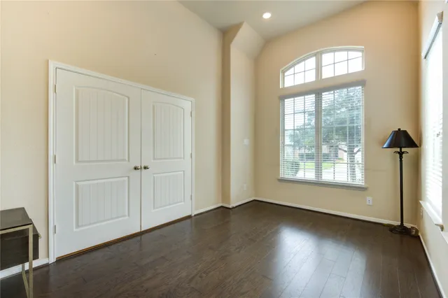 an empty room with wooden floor and windows