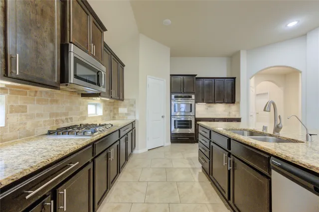 a kitchen with stainless steel appliances granite countertop a sink stove and refrigerator
