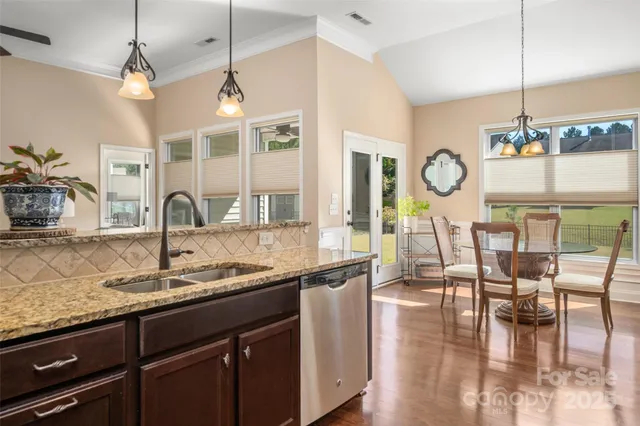 a kitchen with granite countertop a sink a stove and a clock on the wall