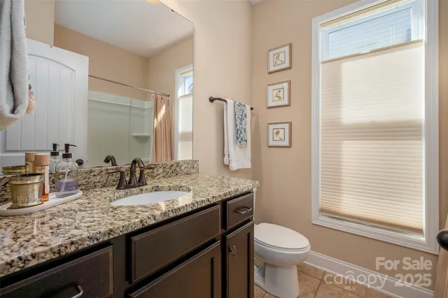 a bathroom with a granite countertop sink toilet and mirror