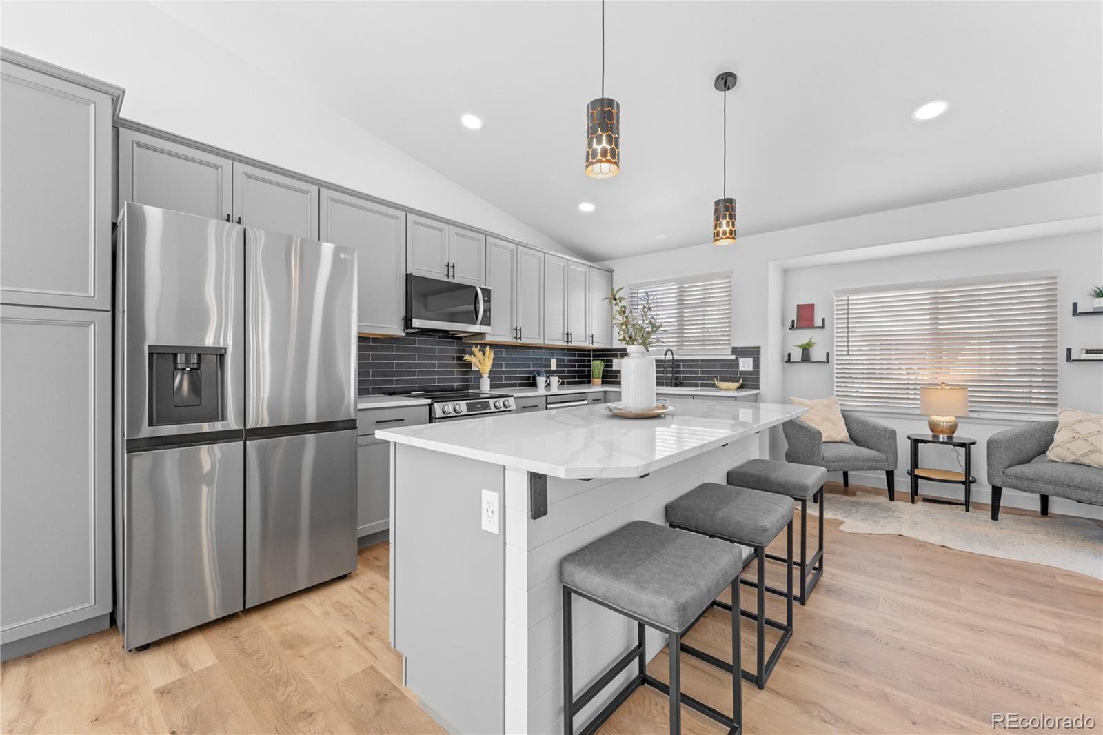 4865 Apollo Bay Drive Highlands Ranch, CO 80130 - Photo 11 of 38 a kitchen with kitchen island a refrigerator a stove a dining table and chairs with wooden floor