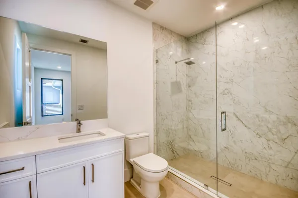 a bathroom with a shower sink mirror and toilet