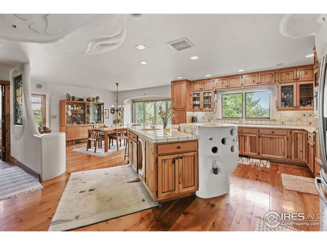 a kitchen with stainless steel appliances granite countertop a refrigerator a stove top oven a dining table and chairs with wooden floor