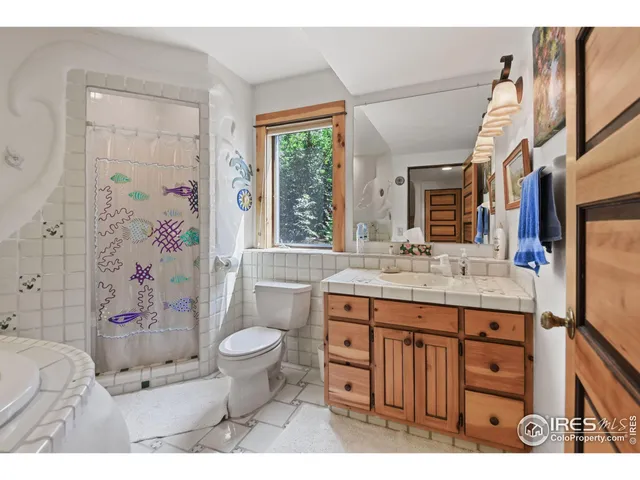 a bathroom with a granite countertop toilet a sink a mirror a shower curtain