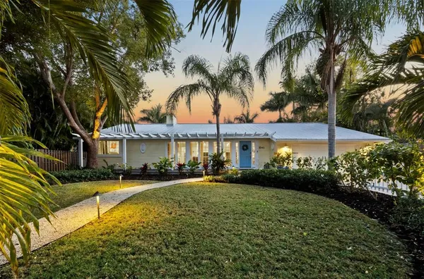a view of a house with a yard and palm trees