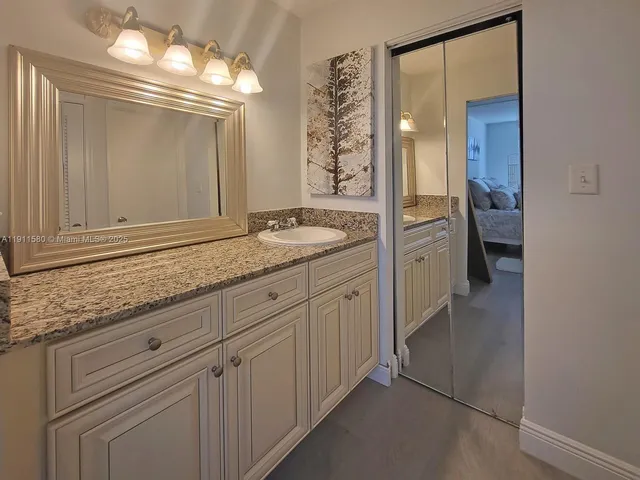 a bathroom with a granite countertop sink and a mirror
