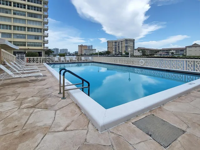 a view of swimming pool with outdoor seating and a buildings in the background