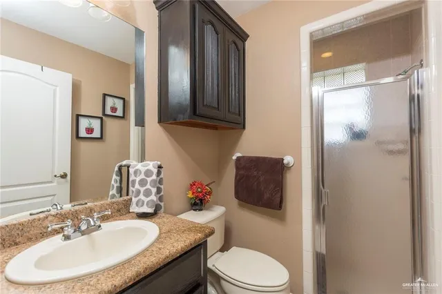 a bathroom with a granite countertop toilet sink and mirror