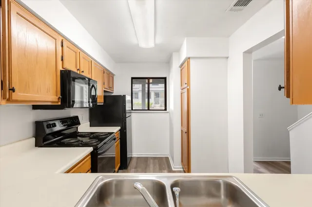 a kitchen with stainless steel appliances granite countertop a refrigerator a stove and a sink with wooden floor