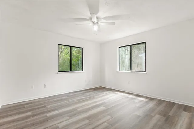 an empty room with windows and fan