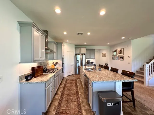 a kitchen with stainless steel appliances granite countertop a stove a sink dishwasher a microwave oven with cabinets and wooden floor