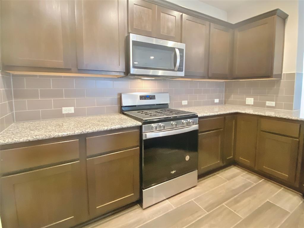 8901 Panhandle Drive Austin, TX 78747 - Photo 9 of 21 Kitchen featuring rich wood cabinetry, stainless steel appliances, speckled countertops, and a subway tile backsplash