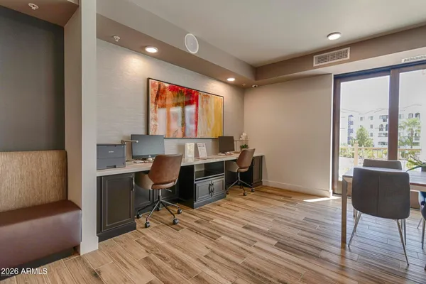 a room with a chair and white cabinets with wooden floor