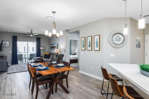 a dining room with wooden floor a chandelier a wooden table and chairs