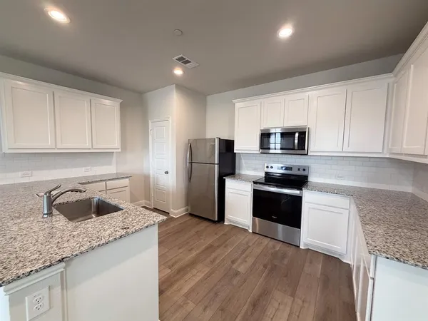 a kitchen with granite countertop a refrigerator stove and sink