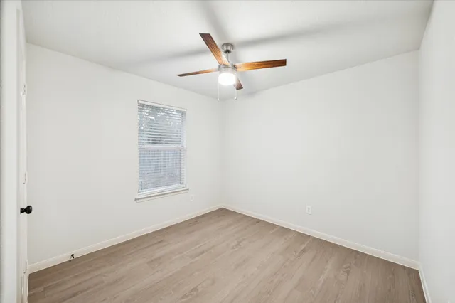 an empty room with a ceiling fan and wooden floor