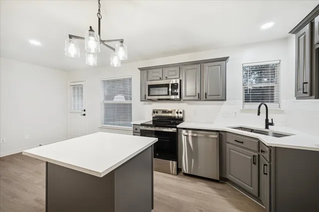 a kitchen with a sink a stove a refrigerator cabinets and a window