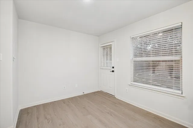 a view of an empty room with wooden floor and a window