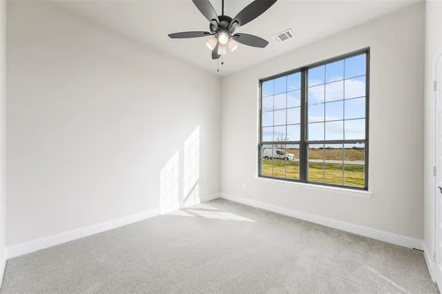 an empty room with windows and fan