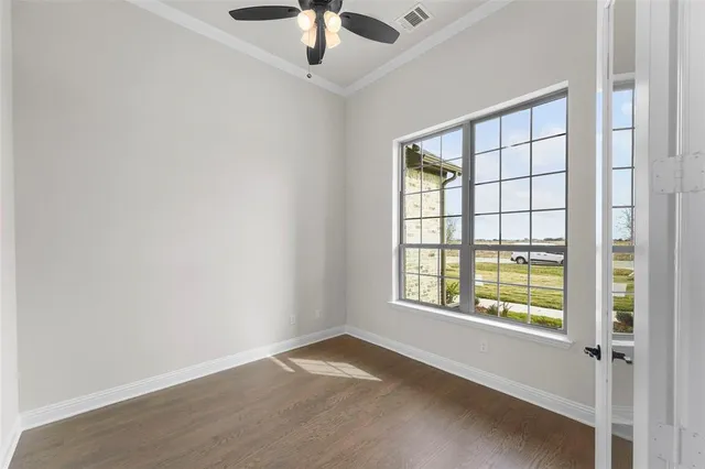 an empty room with windows and ceiling fan