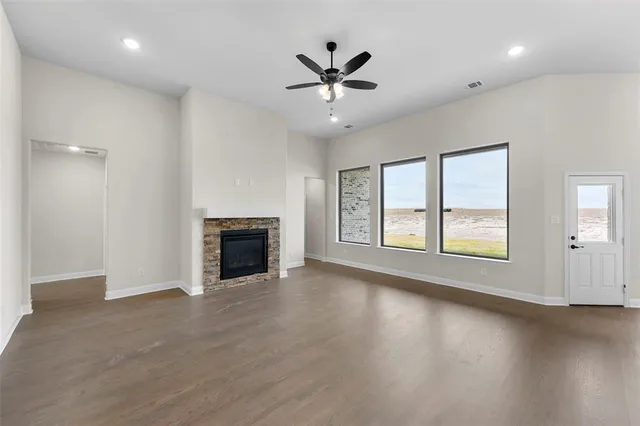 an empty room with windows and ceiling fan