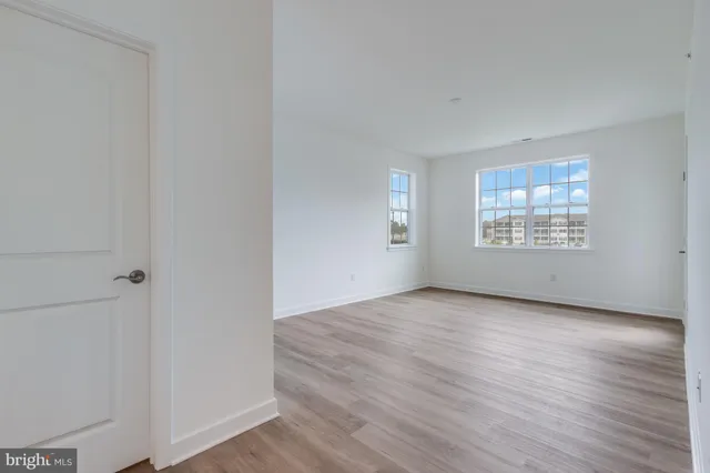 an empty room with wooden floor cabinet and windows