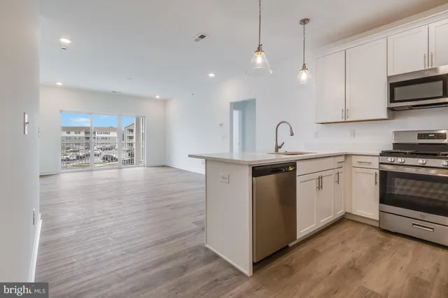 a kitchen with stainless steel appliances granite countertop a sink a stove a refrigerator and island with wooden floor