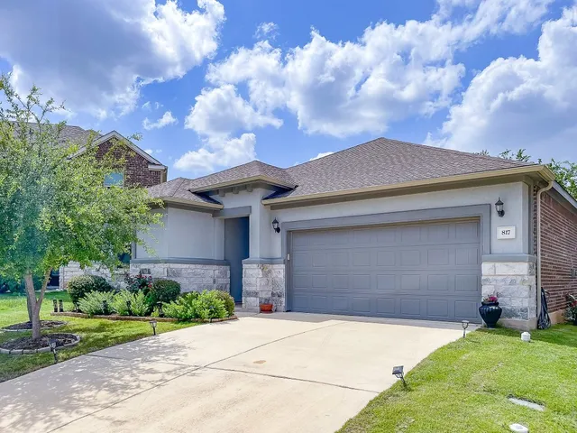 a front view of a house with a garden and trees