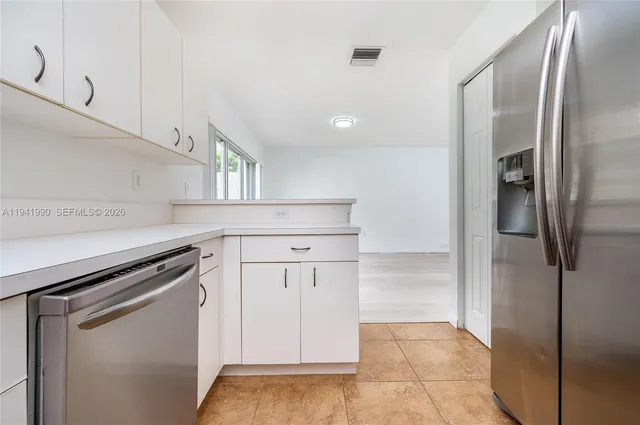 a kitchen with white cabinets and refrigerator