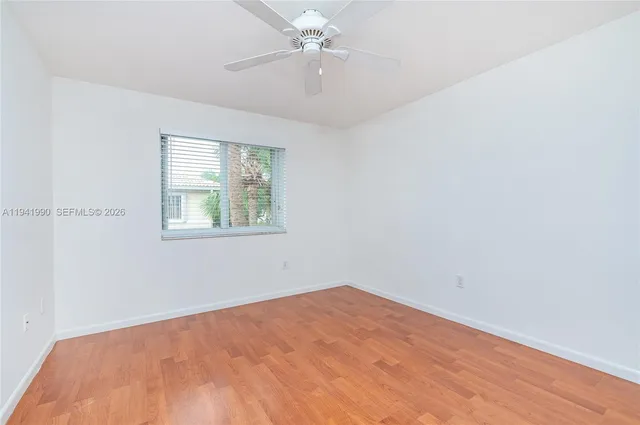 an empty room with a window and ceiling fan
