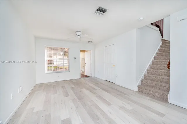 a view of an empty room with wooden floor and windows