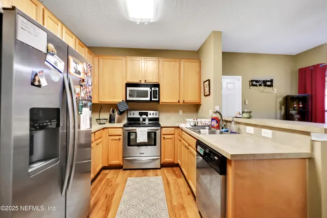 a kitchen with stainless steel appliances a refrigerator sink stove microwave and cabinets