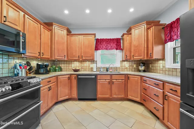 a kitchen with stainless steel appliances granite countertop a stove top oven a sink dishwasher and cabinets with wooden floor