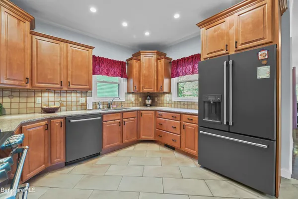 a kitchen with stainless steel appliances granite countertop a refrigerator and wooden cabinets