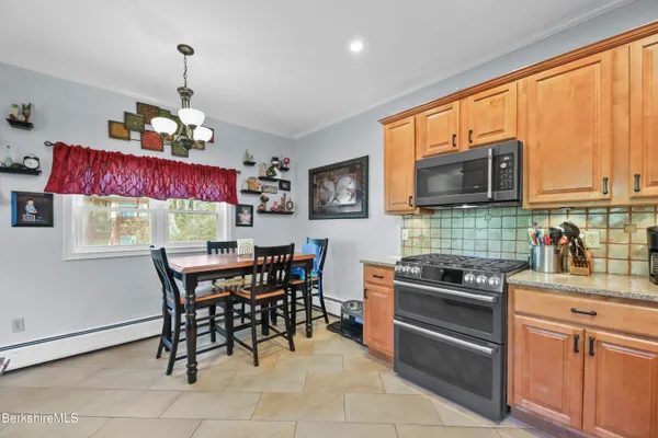 a kitchen with stainless steel appliances granite countertop a stove top oven a sink dishwasher a dining table and chairs with wooden floor