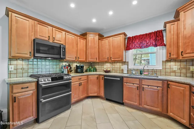 a kitchen with stainless steel appliances granite countertop wooden cabinets a stove top oven a sink and dishwasher