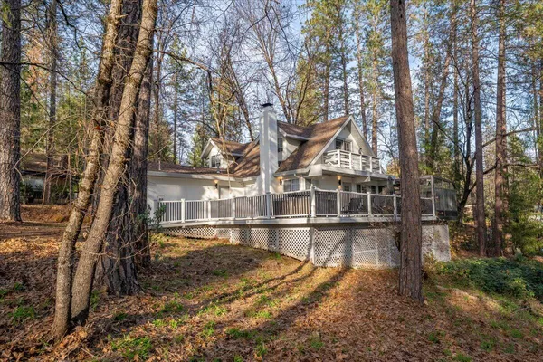a view of a house with large trees and wooden fence