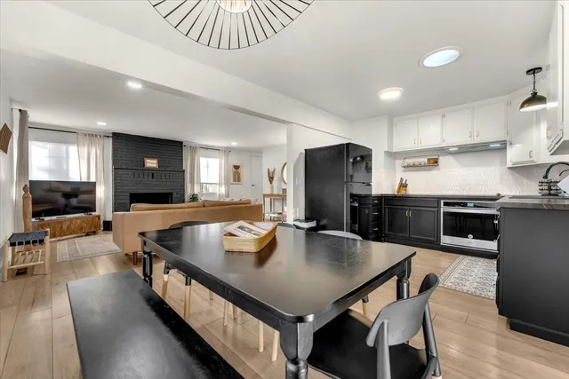 a kitchen with stainless steel appliances granite countertop a stove a refrigerator a kitchen island a sink dishwasher a dining table and chairs with wooden floor